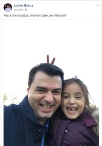 Me dhëmbin e rënë dhe dy gishtat lart, Basha dhe vajza e tij urojnë Krishtlindjen