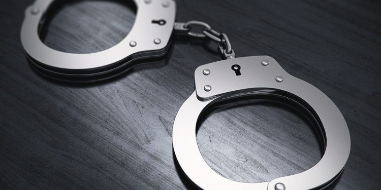 Macro view of metal handcuffs on black wooden office table with selective focus effect