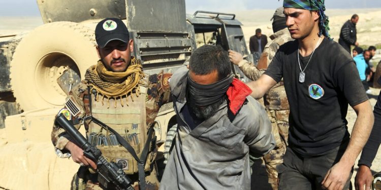 FILE - In this Feb. 25. 2017 file photo, Iraqi special forces arrest a fighter with Islamic State militia in Mosul, Iraq. The Islamic State group erupted from the chaos of Syria and Iraq's conflicts and swiftly did what no Islamic militant group had done before, conquering a giant stretch of territory and declaring itself a "caliphate." U.S. officials said late Saturday that their shadowy leader Abu Bakr al-Baghdadi was the target of an American raid in Syria and may have died in an explosion. (AP Photo/Khalid Mohammed, File)