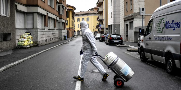 A staffer delivers a medical oxygen tank to coronavirus patients who are being treated at home, in Bergamo, one of the areas worst affected by the virus, Northern Italy, Tuesday, March 31, 2020. The new coronavirus causes mild or moderate symptoms for most people, but for some, especially older adults and people with existing health problems, it can cause more severe illness or death. (Claudio Furlan/LaPresse via AP)