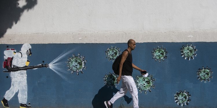 RIO DE JANEIRO, BRAZIL - JUNE 08: A man walks past a wall with a graffiti depicting a cleaner in protective gear spraying viruses with the face of President Jair Bolsonaro in Estacio neighborhood amidst the coronavirus (COVID-19) pandemic on June 8, 2020 in Rio de Janeiro, Brazil. (Photo by Bruna Prado/Getty Images)