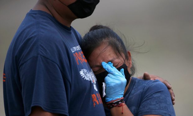 A couple wearing masks and gloves to protect themselves from the new coronavirus mourn during the burial of their loved one at the newly constructed Valle de Chalco Municipal Cemetery, built to accommodate the rise in deaths amid the new coronavirus pandemic, on the outskirts of Mexico City, Thursday, May 21, 2020. (AP Photo/Marco Ugarte)