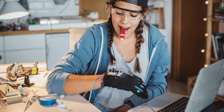 Teenage girl working on some engineering project at home.  Working table full of different tools and items needed for repairing electrical circuits.