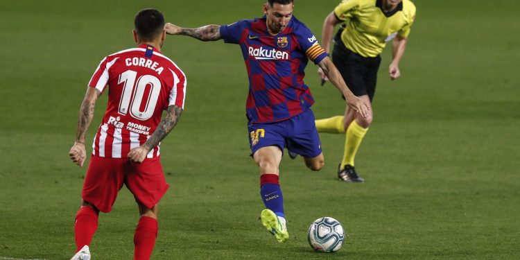 Barcelona's Lionel Messi, center, kicks the ball in front Atletico Madrid's Angel Correa during the Spanish La Liga soccer match between FC Barcelona and Atletico Madrid at the Camp Nou stadium in Barcelona, Spain, Tuesday, June 30, 2020. (AP Photo/Joan Monfort)