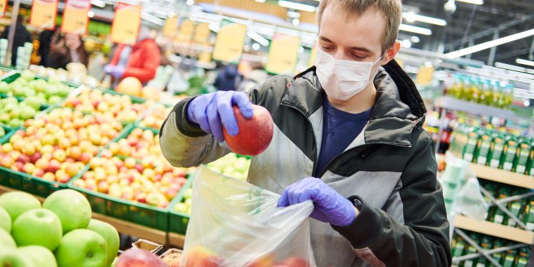 man in mask and protective gloves buying fruit food it supermarket shop during quarantine for covid-19 virus outbreak