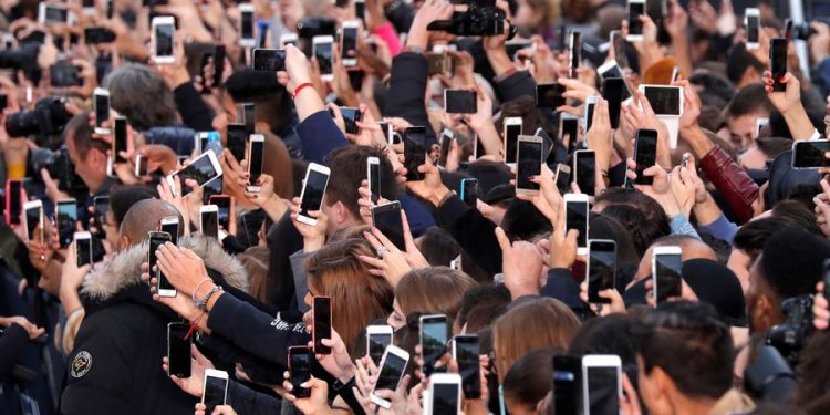 People use their smartphone to take photos of the L'Oreal fashion show on the Champs Elysees avenue during a public event organized by French cosmetics group L'Oreal as part of Paris Fashion Week, France, October 1, 2017.  REUTERS/Charles Platiau     TPX IMAGES OF THE DAY - RC1CAB6813E0