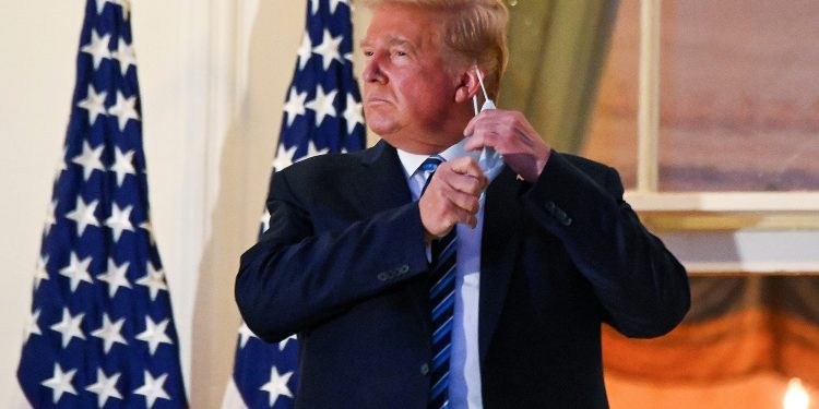 U.S. President Donald Trump pulls off his protective face mask as he poses atop the Truman Balcony of the White House after returning from being hospitalized at Walter Reed Medical Center for coronavirus disease (COVID-19) treatment, in Washington, U.S. October 5, 2020. REUTERS/Erin Scott