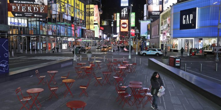 A woman walks through a nearly deserted Times Square in New York Monday, as the city adjusts to widespread closures and restrictions on public life because of the COVID-19 respiratory disease.