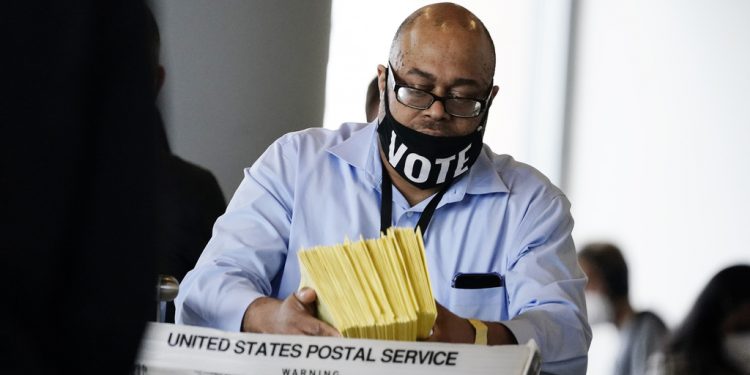 A election worker hands out ballots to be counted at State Farm Arena on Thursday, Nov. 5, 2020, in Atlanta. (AP Photo/Brynn Anderson)