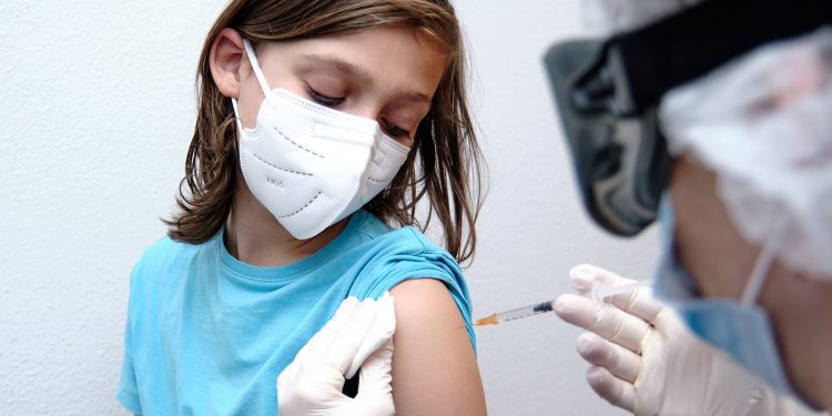 Female doctor giving covid-19 vaccine to a boy