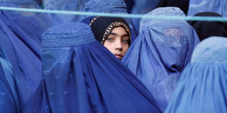 A girl looks on among Afghan women lining up to receive relief assistance, during the holy month of Ramadan in Jalalabad, Afghanistan, June 11, 2017. REUTERS/Parwiz - RTS16JM5