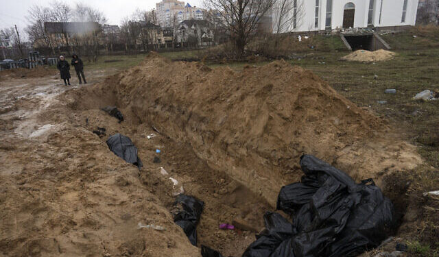 Neighbours gather next to a mass grave in Bucha, in the outskirts of Kyiv, Ukraine, Sunday, April 3, 2022. (AP Photo/Rodrigo Abd)