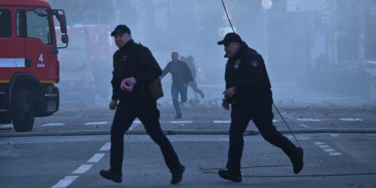 Local residents and police officers run after a drone attack in Kyiv on October 17, 2022, amid the Russian invasion of Ukraine. - Ukraine officials said on October 17, 2022 that the capital Kyiv had been struck four times in an early morning Russian attack with Iranian drones that damaged a residential building and targeted the central train station. (Photo by Sergei SUPINSKY / AFP) (Photo by SERGEI SUPINSKY/AFP via Getty Images)