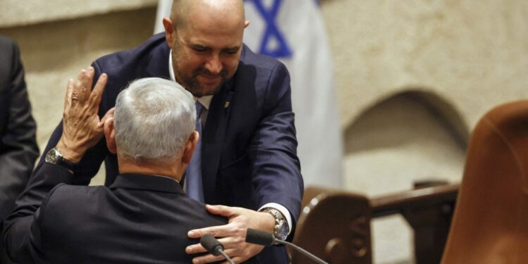 Israel's new speaker of the Knesset (parliament) Amir Ohana (top) congratulates Prime Minister Benjamin Netanyahu as the new government is sworn in, in Jerusalem on December 29, 2022. - Netanyahu was sworn in as prime minister after a stint in opposition, heading what analysts call the most right-wing government in the country's history. (Photo by AMIR COHEN / POOL / AFP)