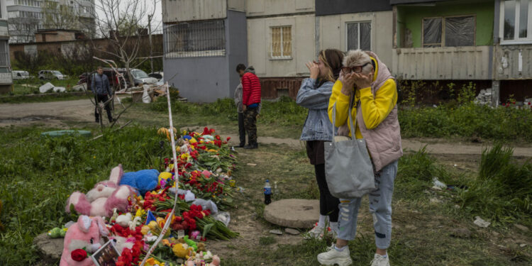 Women cry next to a memorial for the victims who died during Friday's Russian attack on a residential building in Uman, central Ukraine, Sunday, April 30, 2023. (AP Photo/Bernat Armangue)