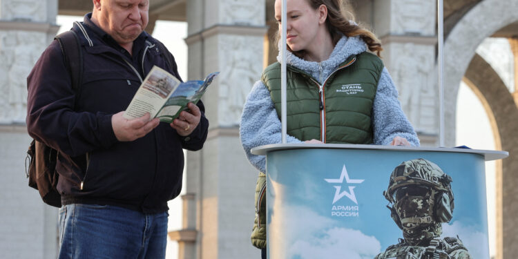 FILE PHOTO: A man studies a leaflet given by a campaign member promoting Russian army service in Moscow, Russia April 12, 2023.  REUTERS/Yulia Morozova