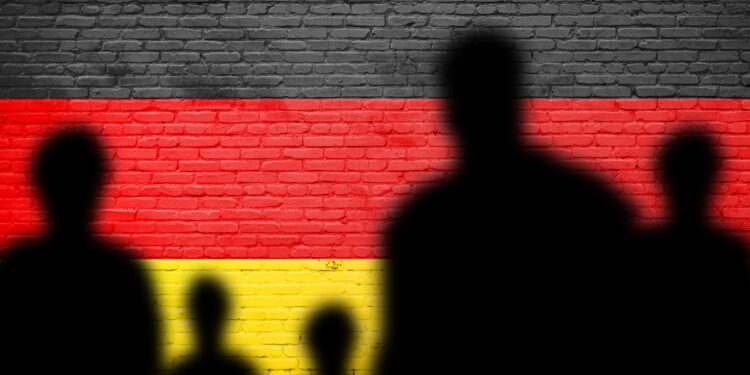 The refugees migrate to Germany . Germany flag painted on a brick wall