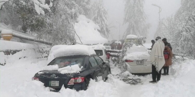 FILE PHOTO: People stand next to cars stuck under fallen trees on a snowy road, in Murree, northeast of Islamabad, Pakistan in this still image taken from a video January 8, 2022. PTV/REUTERS TV via REUTERS/File Photo