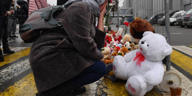 A woman mourns at a makeshift memorial in front of the Crocus City Hall, a day after a gun attack in Krasnogorsk, outside Moscow, on March 23, 2024. Camouflaged assailants opened fire at the packed Crocus City Hall in Moscow's northern suburb of Krasnogorsk on March 22, 2024, evening ahead of a concert by Soviet-era rock band Piknik in the deadliest attack in Russia for at least a decade. Russia on March 23, 2024, said it had arrested 11 people - including four gunmen - over the attack on a Moscow concert hall claimed by Islamic State, as the death toll rose to over 100 people. (Photo by Olga MALTSEVA / AFP) (Photo by OLGA MALTSEVA/AFP via Getty Images)