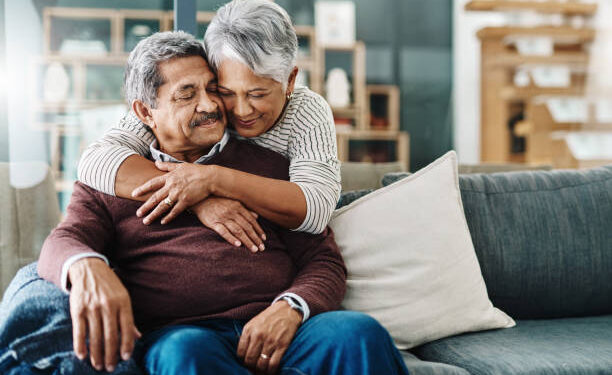 Cropped shot of a cheerful elderly woman hugging her husband who's in a wheelchair at home during the day