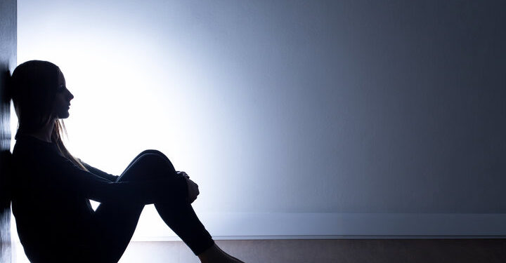 Teenager with depression sitting alone in dark room