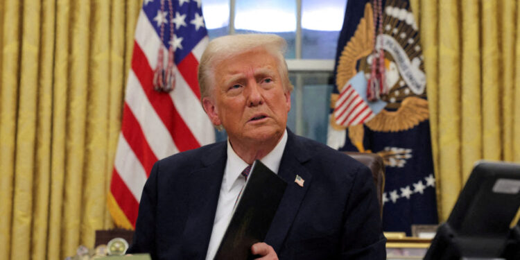 FILE PHOTO: U.S. President Donald Trump signs documents as he issues executive orders and pardons for Jan. 6 defendants in the Oval Office at the White House on Inauguration Day in Washington, U.S., January 20, 2025. REUTERS/Carlos Barria/File Photo