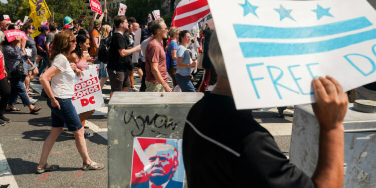 Demonstrators pass by an image of U.S. President Donald Trump during the "We Are All D.C." march to protest against the National Guard troops, in Washington, D.C., U.S., September 6, 2025. REUTERS/Daniel Becerril