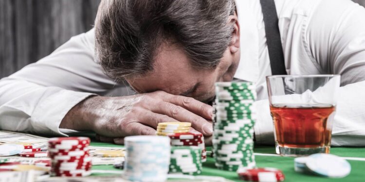 It is not my day. Depressed senior man in shirt and suspenders leaning his head at the poker table with money and gambling chips laying all around him
